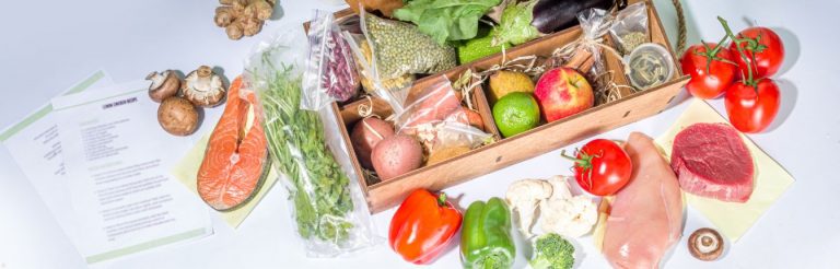 A meal kit opened on a white surface, with all the ingredients and recipe card laid out.
