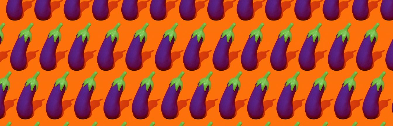 Rows of fake eggplants on a bright orange background.