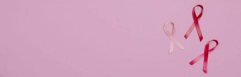 Three breast cancer ribbons on a light pink background.