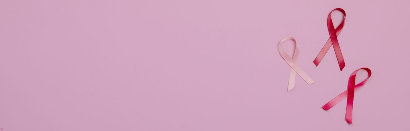 Three breast cancer ribbons on a light pink background.