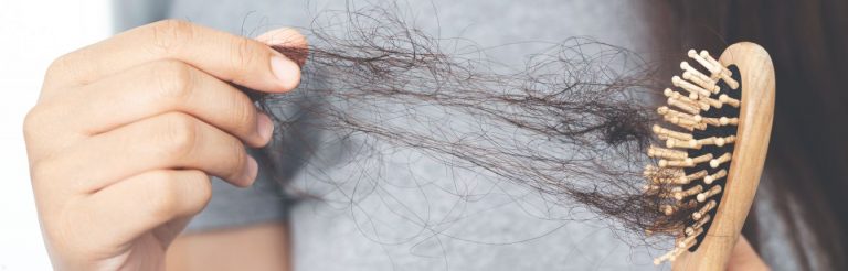 A woman pulling lots of loose hair out of a brush.