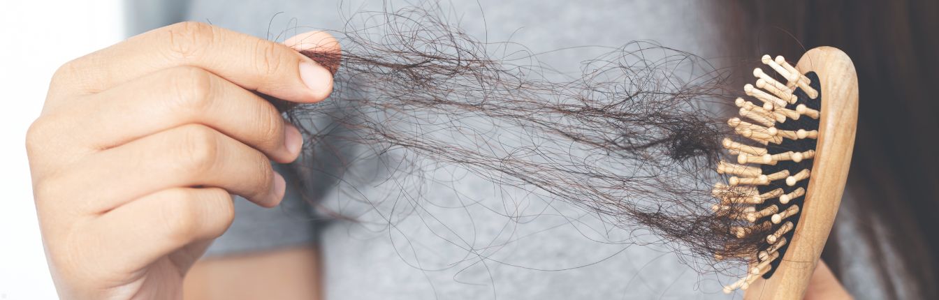 A woman pulling lots of loose hair out of a brush.